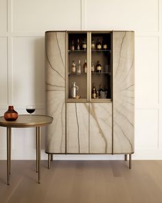 a marble cabinet with wine glasses on it and a table in the corner next to it