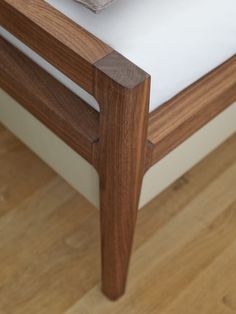 a close up of a bed with a wooden frame and white sheets on top of it