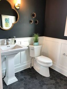 a white toilet sitting next to a sink in a bathroom under a large round mirror