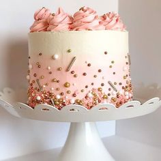 a pink and white cake with gold sprinkles on it sitting on a plate