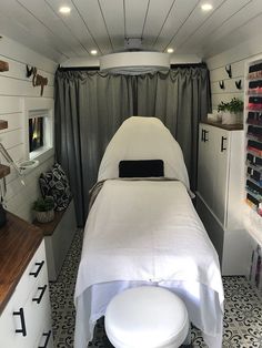 a white bed sitting in the middle of a room next to a counter and shelves