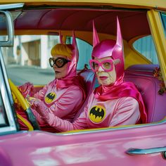 two women in pink costumes sitting in a car