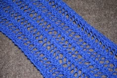 a blue crocheted scarf is laying on the floor