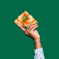 a hand holding up a piece of pizza