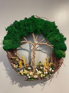 a wreath made out of branches with flowers and leaves on it, hanging from the wall