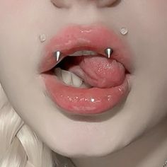 a close up of a woman's lips with piercings on her nose and tongue