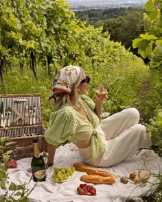 a woman sitting on the ground with food and wine