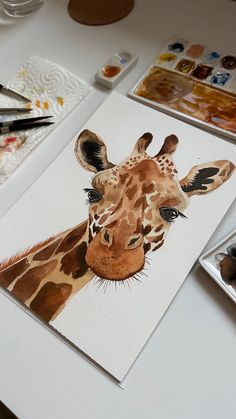 a painting of a giraffe on a table with paint and watercolors