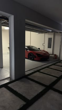 a red sports car is parked in a garage with its door open to reveal it's own parking space