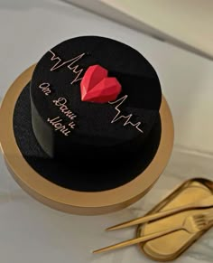 there is a black hat with a red heart on it next to some gold scissors