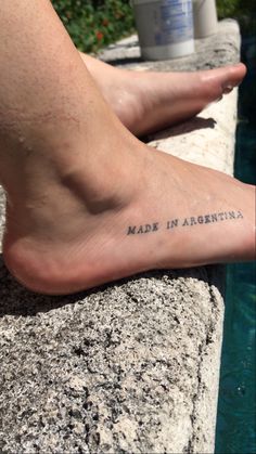 a person's foot with the words made in argentina written on it next to a pool