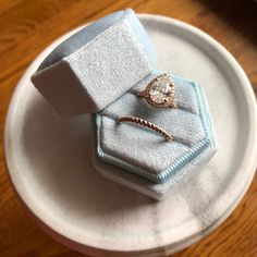 two rings are sitting on top of each other in a ring box that sits on a plate