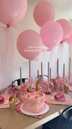 a table topped with a cake and lots of pink balloons in the shape of hearts