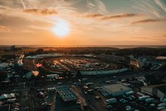 an aerial view of a race track with cars parked in the lot and sunset behind it