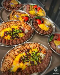 several trays filled with different types of food on top of a metal countertop