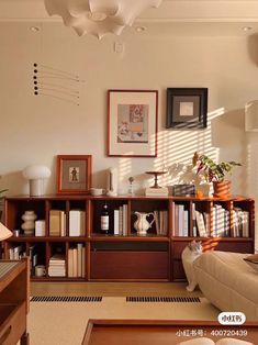 a living room filled with furniture and bookshelves next to a wall mounted art piece