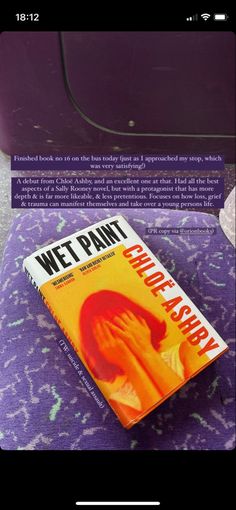 a book sitting on top of a purple blanket next to a suitcase with the words wet paint written on it