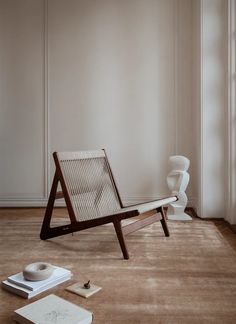 a chair sitting on top of a wooden floor next to a white vase and book