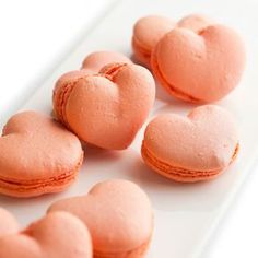 pink macaroons arranged in the shape of hearts on a white plate