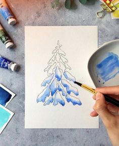 someone is painting a christmas tree with watercolors