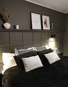 a black and white bed with two framed pictures on the wall above it's headboard