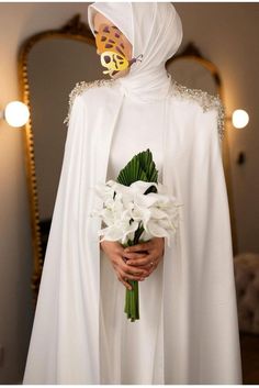 a person in a white cloak holding flowers