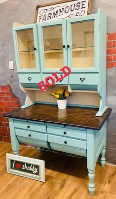 a blue hutch sitting on top of a hard wood floor next to a brick wall