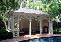 a gazebo sitting next to a pool surrounded by trees