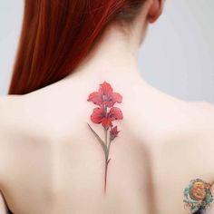 a woman's back tattoo with red flowers on her shoulder