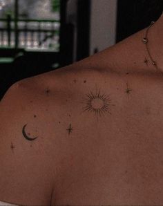 the back of a woman's shoulder with stars and a sun tattoo on it