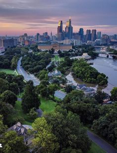 an aerial view of the city skyline and river at sunset with trees in foreground