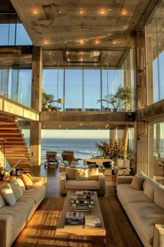 a living room filled with lots of furniture next to an ocean side house on top of a hill