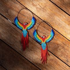 pair of hoop earrings with multicolored beads on wooden floor next to wood plank