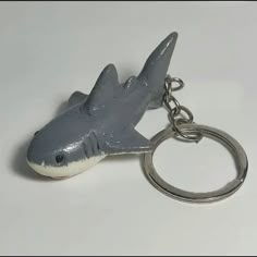 a shark shaped keychain is shown on a white surface