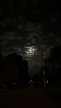 the full moon shines brightly in the night sky over a street lined with trees