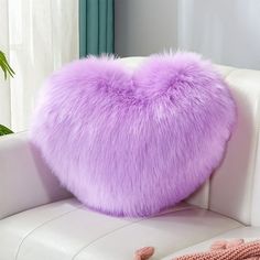 a purple heart shaped pillow sitting on top of a white couch