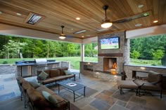 an outdoor living room with fireplace and television