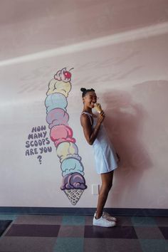 a woman standing in front of a wall with an ice cream cone on it