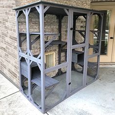 a large gray bird house sitting on top of a sidewalk next to a brick building