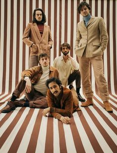 four men are posing in front of a striped background