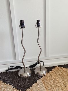 two metal candles are sitting on the floor