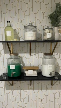 the shelves are filled with different types of candles and soaps on display in front of a wallpapered background