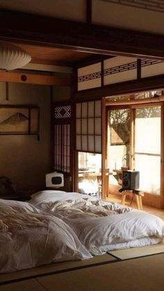 a bed with white sheets and pillows in a room next to an open door that leads to another room