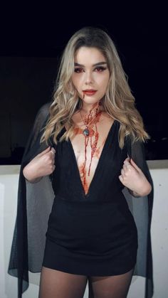 a woman with blood on her chest and black bodysuit, posing for the camera