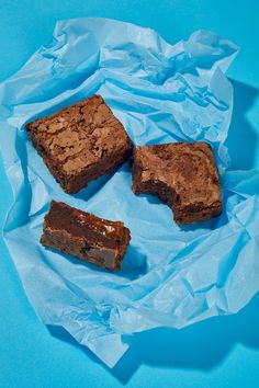 three pieces of brownie sitting on top of blue paper