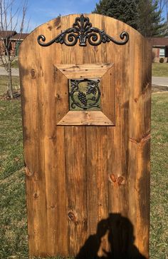 a wooden door with an iron decoration on the top and bottom part, sitting in grass