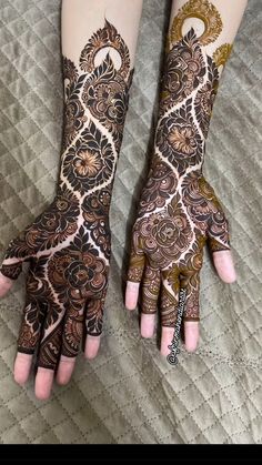 two hands with henna tattoos on them, one is showing off the intricate design