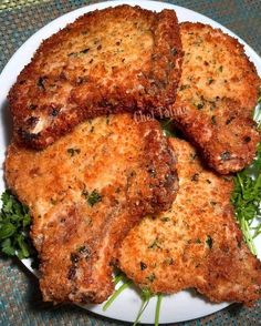 four pieces of fried meat on a white plate with green garnishes and parsley