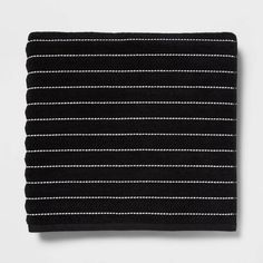 the black and white striped scarf is folded on top of a white surface with pins