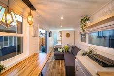 a living room filled with furniture next to a wooden table and window covered in plants